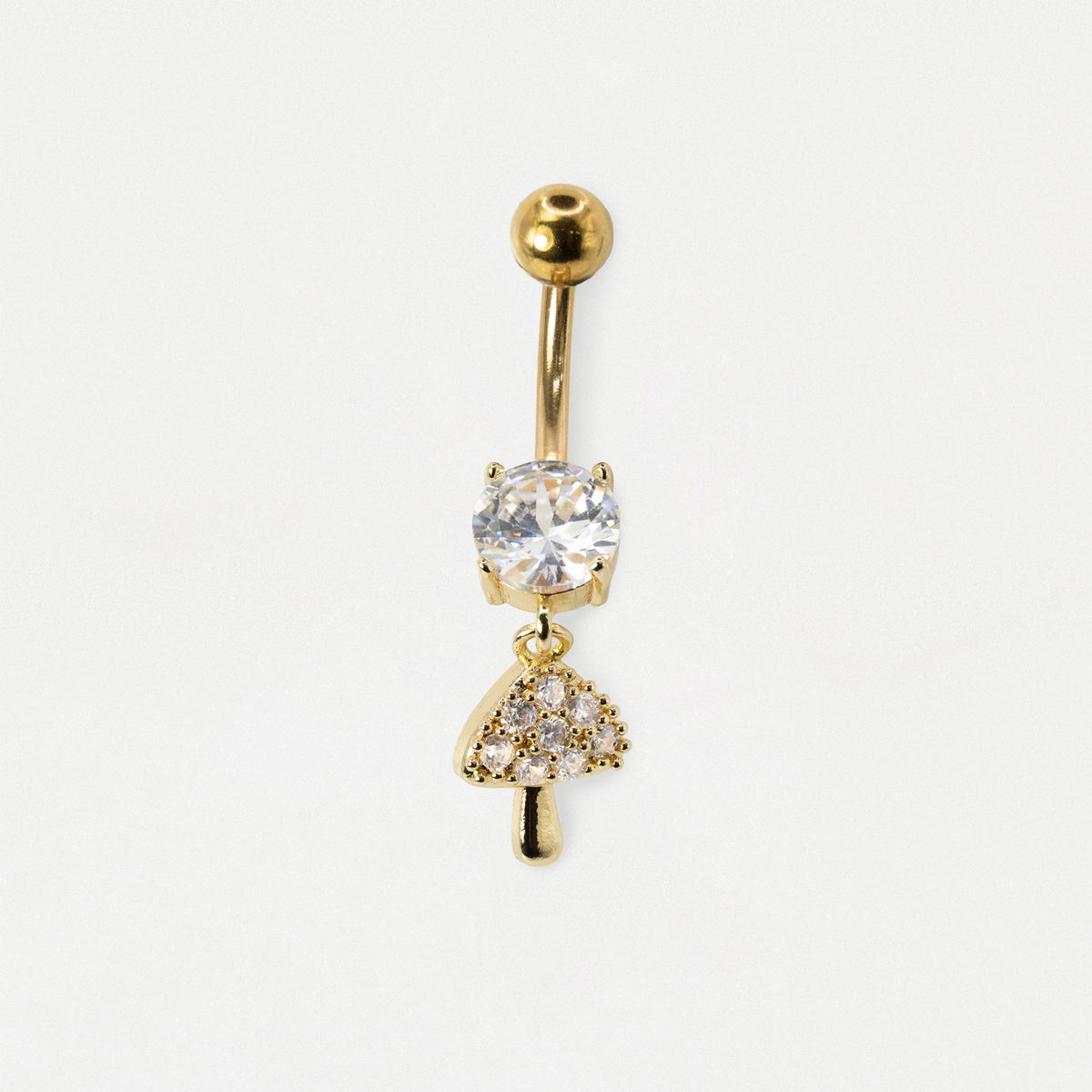 A gold-plated belly button ring featuring a dangling mushroom charm. The charm is detailed with clear crystals, including a large round crystal on the mushroom cap and smaller crystals on the stem and border.