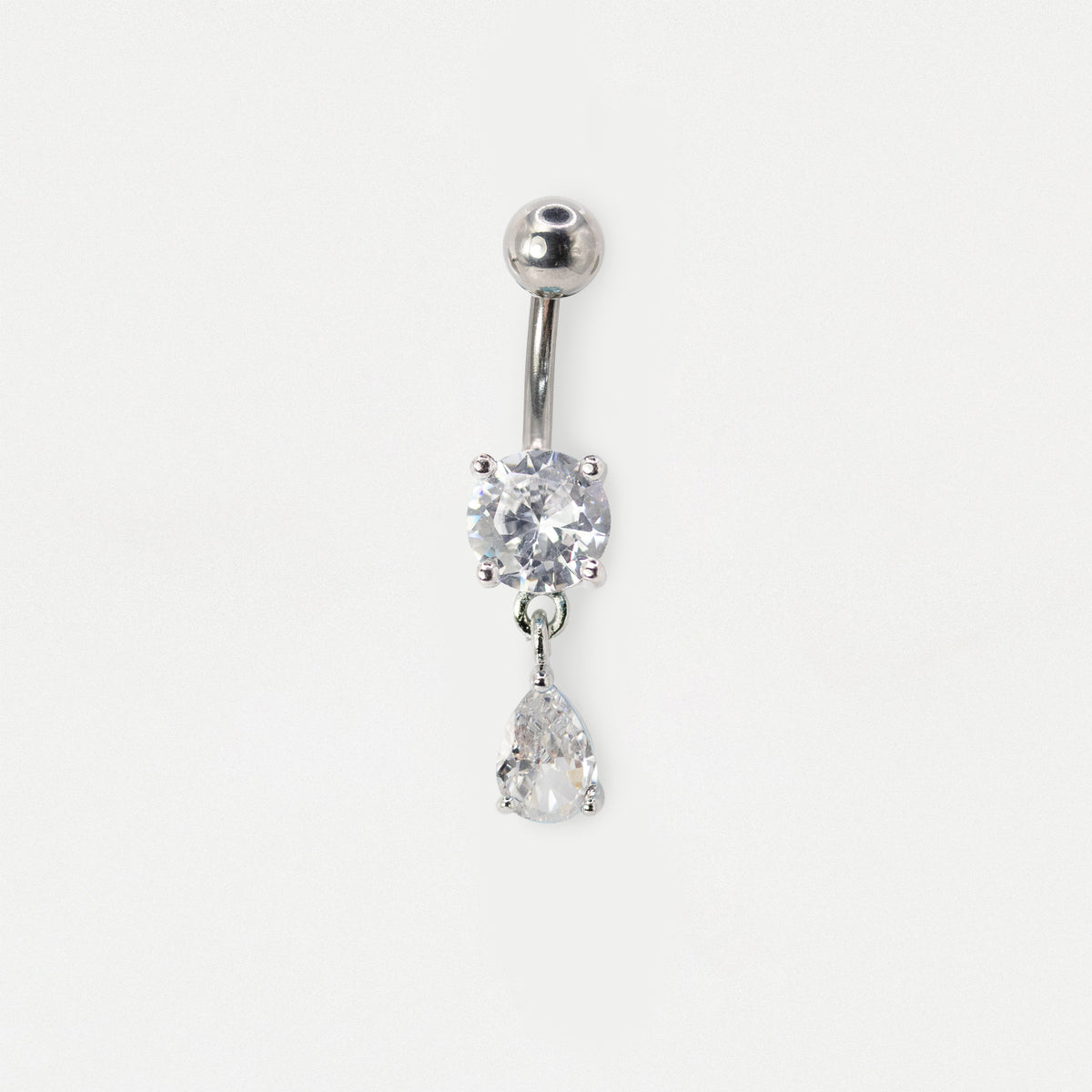 A silver-toned belly button ring featuring a round bezel-set clear crystal and a dangling pear-cut clear crystal, shown on a plain white background.