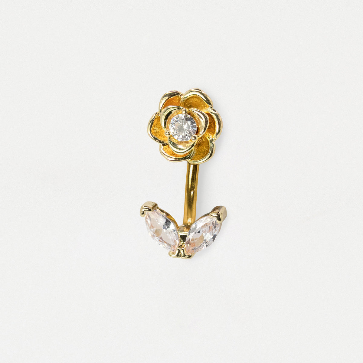 A gold flower-shaped body jewelry piece with a clear round gemstone in the center of the flower and two marquise-cut clear crystals below, shown on a plain light gray background.