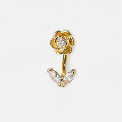 A gold flower-shaped body jewelry piece with a clear round gemstone in the center of the flower and two marquise-cut clear crystals below, shown on a plain light gray background.