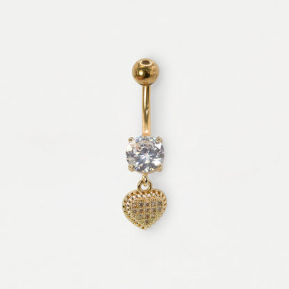 Head on image of a gold steel belly bar with a large claw-set round clear crystal and a dangly heart with clear crystal pavé gemstones by Kingsley Ryan Wholesale