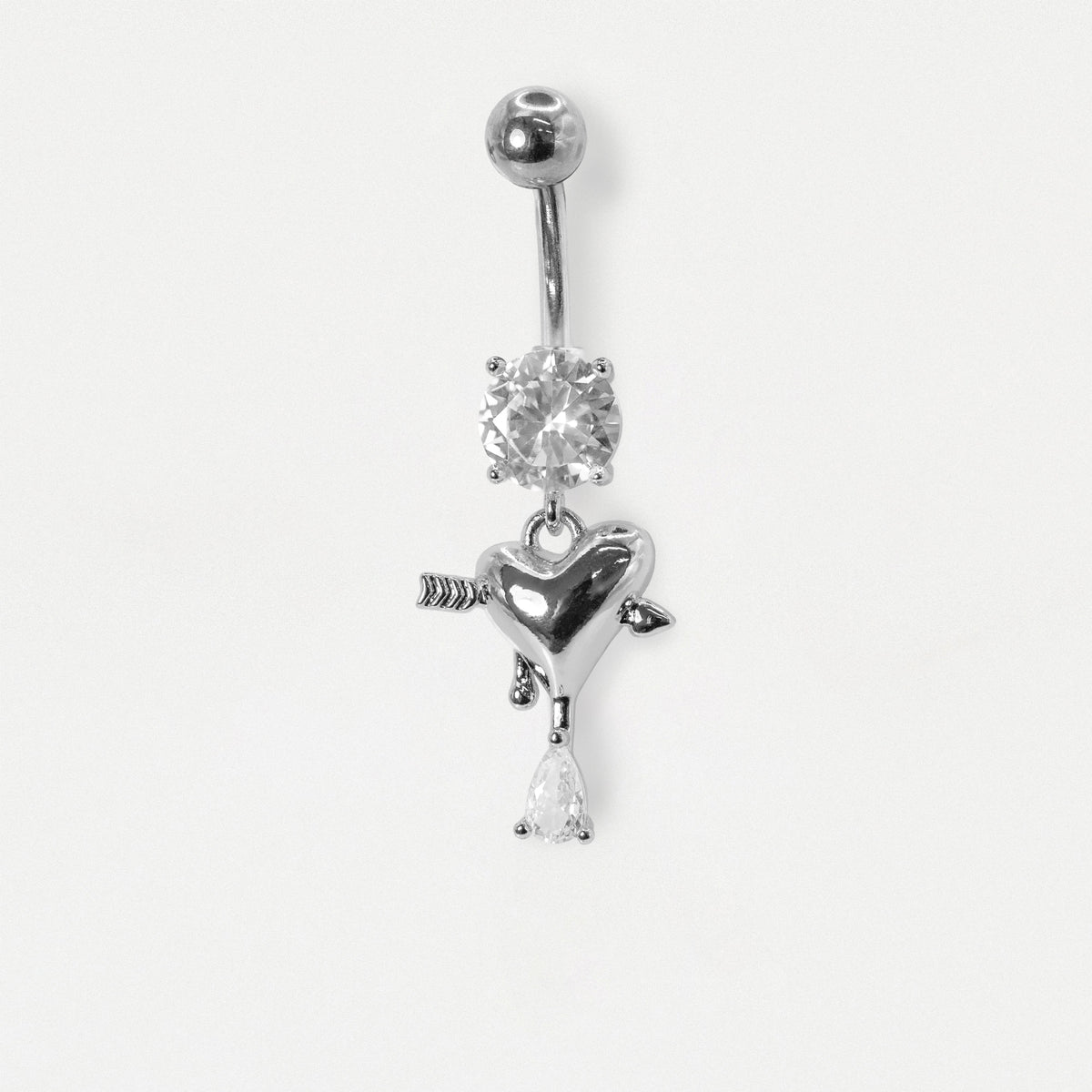 A Steel belly bar on a white background with a clear crystal and a dangly heart with an arrow and  a pear crystal drop by Kingsley Ryan Wholesale