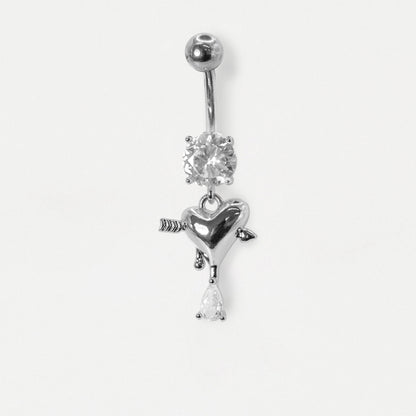A Steel belly bar on a white background with a clear crystal and a dangly heart with an arrow and  a pear crystal drop by Kingsley Ryan Wholesale
