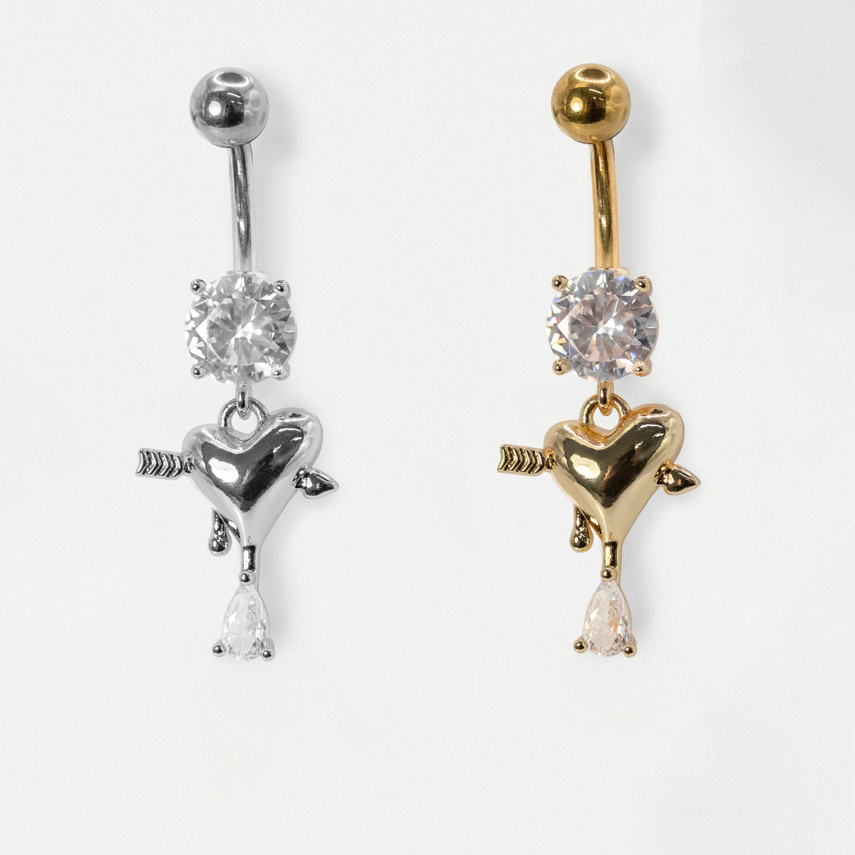 316L Grade Steel and Gold PVD Steel belly bars featuring a round clear crystal solitaire and an arrow-pierced heart charm dangle with a pear crystal drop by Kingsley Ryan Wholesale