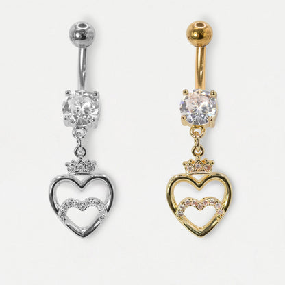 An image on a white background of a 316L Grade Steel and a Gold PVD Steel belly bar featuring a round clear crystal solitaire and an open heart dangle charm topped with a mini crown and clear crystal pavé by Kingsley Ryan Wholesale