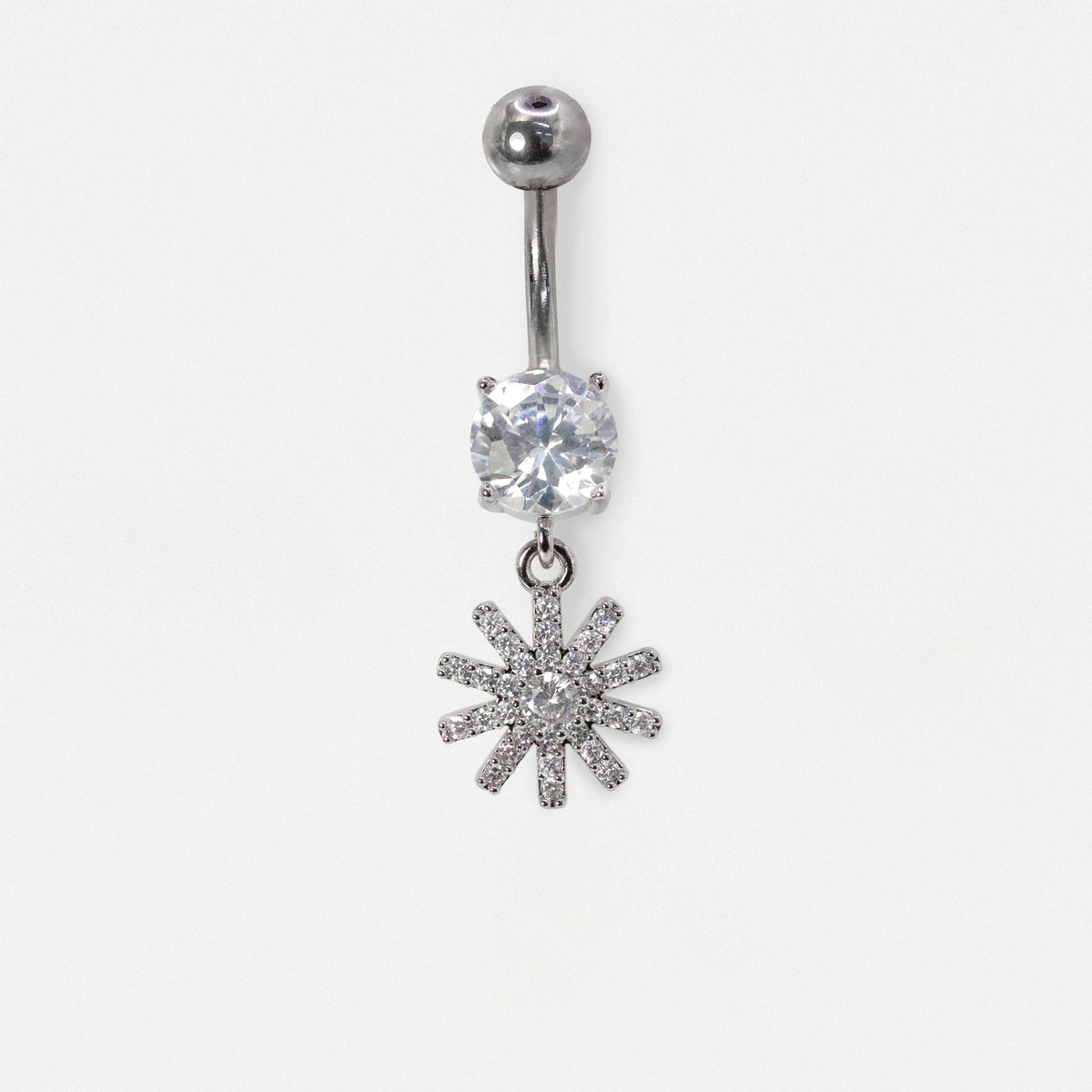 Front view of a  Steel belly bar featuring a claw-set round clear crystal solitaire and a dangling pavé-set starburst or floral charm with clear crystals by Kingsley Ryan Wholesale