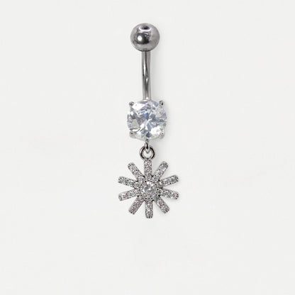 Front view of a  Steel belly bar featuring a claw-set round clear crystal solitaire and a dangling pavé-set starburst or floral charm with clear crystals by Kingsley Ryan Wholesale