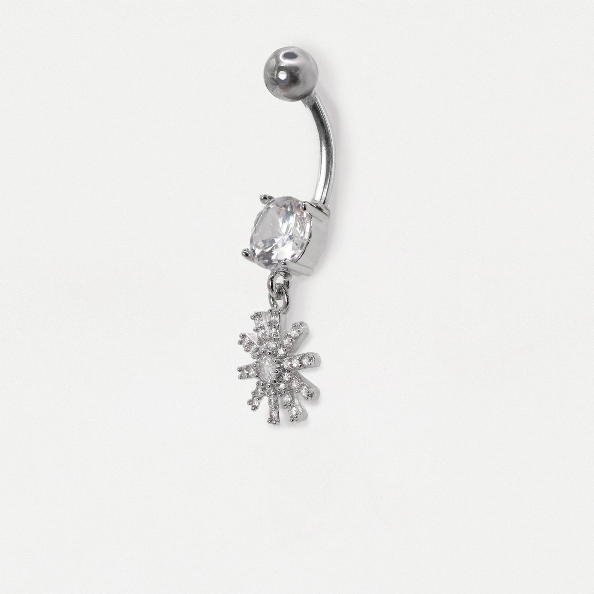 Image on a white background showing a Steel navel bar with a round clear crystal  and a dangly pavé-set starburst or floral charm with clear crystals by Kingsley Ryan Wholesale
