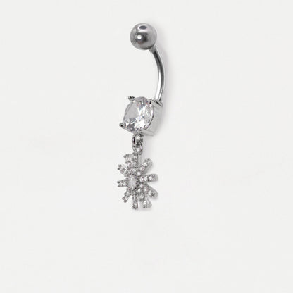 Image on a white background showing a Steel navel bar with a round clear crystal  and a dangly pavé-set starburst or floral charm with clear crystals by Kingsley Ryan Wholesale