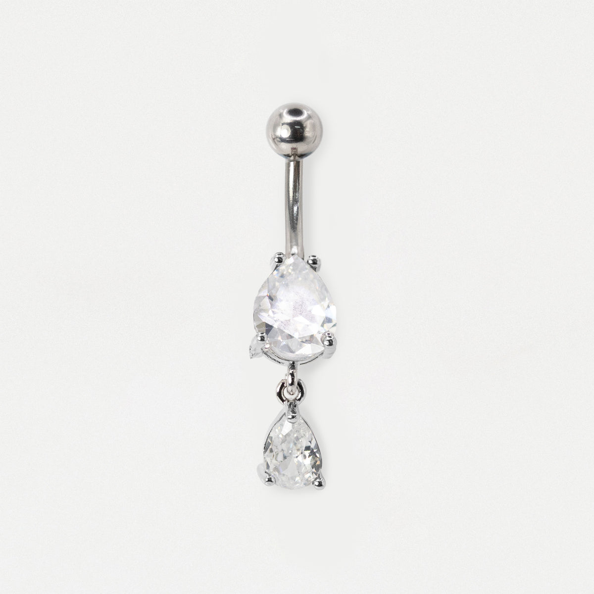 A steel belly button bar featuring two dangling teardrop-shaped clear crystals in a prong setting, by Kingsley Ryan